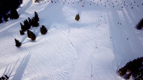 Aerial view of ski resort with people snowboarding down the hill. Stock footage. Flying over the ski