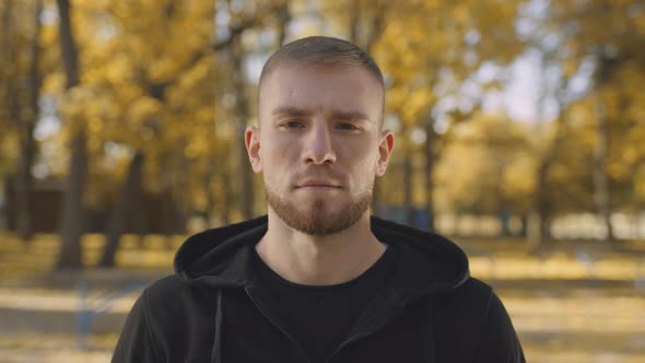 Close Up Portrait of Young Peaceful Bearded Man Looking at Camera Posing in Bright Golden Autumn