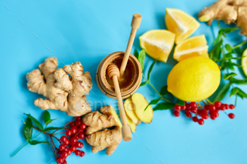 ing foods ginger, lemon,  honey,  guelder rose, mint on blue background Top view, copy space