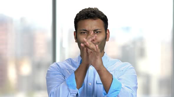 Young Indian Man Grimacing on Blurred Background.