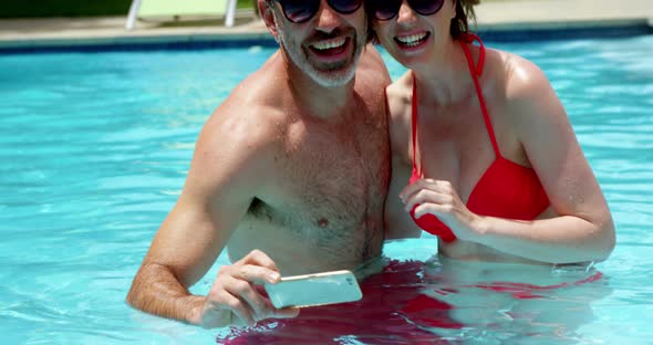 Couple taking a selfie on mobile phone in swimming pool