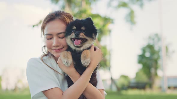 Happy asian woman playing with dog on the park in sunset light, summer vacation.