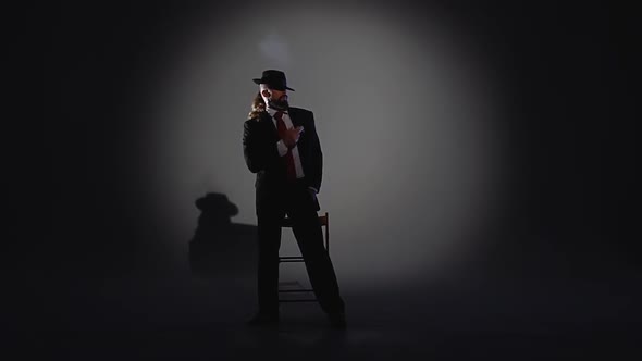 Elegant Man in a Black Hat Is Dancing an Erotic Dance. Spotlight on a Black Background. Close Up