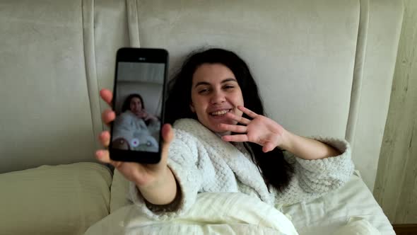 Happy Blogger Shooting Video on the Phone While Laying in Bed