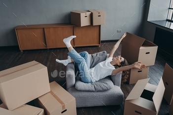 ting hands celebrates relocation to new home in room with cardboard boxes. Happy woman tenant feels success on moving day. Mortgage, first realty.
