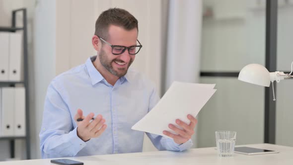 Middle Aged Man Excited By Success on Documents