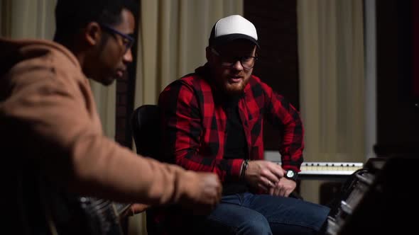 Talented AfroAmerican Guitarist in Glasses Tunes Musical Equipment During Play on Electric Guitar