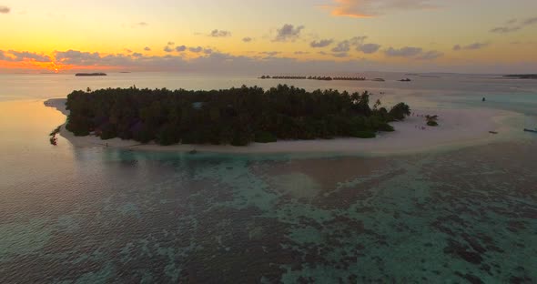 Aerial drone view of a scenic tropical island in the Maldives at sunset.