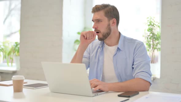 Young Creative Man with Laptop Having Coughing in Modern Office