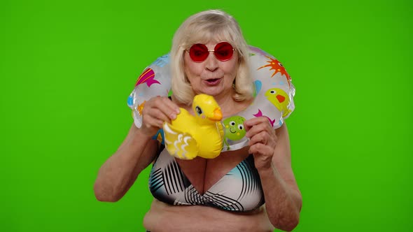 Senior Woman Tourist in Sunglasses Dancing Playing with Inflatable Duck Toy Rubber Swimming Ring