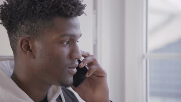 Close-up of Smiling Young Man Talking on Mobile Phone Indoors