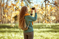 A girl with a smartphone takes photos in an autumn forest - PhotoDune Item for Sale