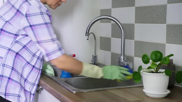 Woman Cleaning Double Chrome Sink in Rubber Gloves Using Spray and Sponge