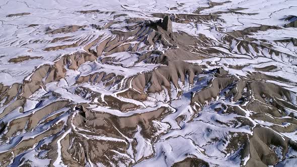 Aerial view flying over desert terrain as snow melts in the landscape