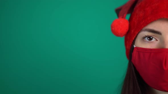 Portrait of Young Woman with Red Medical Face Mask and Santa Hat, Looking at Camera