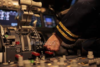 Female copilot pushing dashboard buttons in plane cockpit