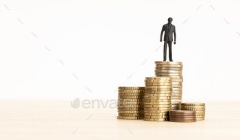 sman figurine standing on a pile of coins. Copy space