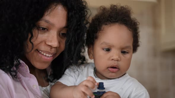 Closeup Cute Curlyhaired African American Boy Eating Tubed Children Food and Happy Woman Talking