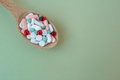 Many different pills in wooden spoon on green background. Copy space. Top view - PhotoDune Item for Sale