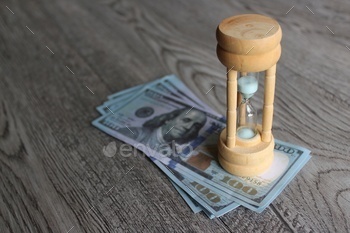 t concept. Hourglass and stack of money on table