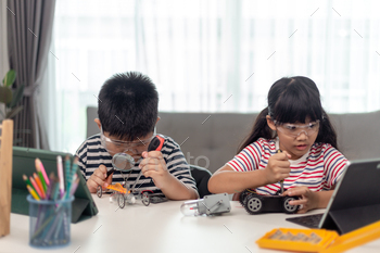 two Asian children having fun learning coding together, learning remotely at home,