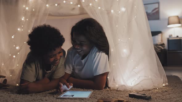 Siblings Using Tablet in Handmade Tent