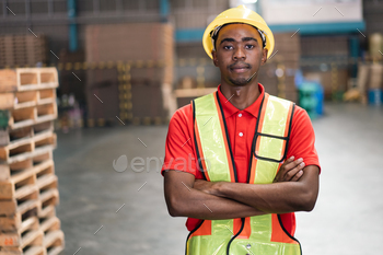 in arms crossed looking at camera at warehouse distribution. Confident employee at industrial factory