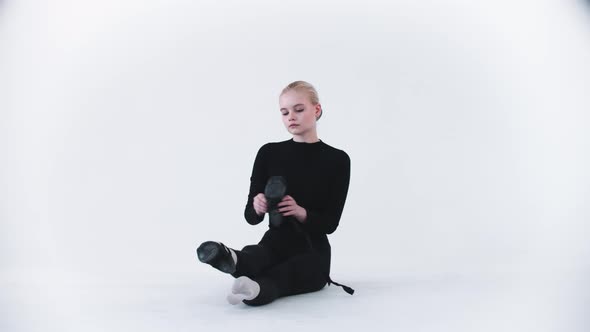 Young Blonde Woman Ballerina Putting on Her Pointe Shoes