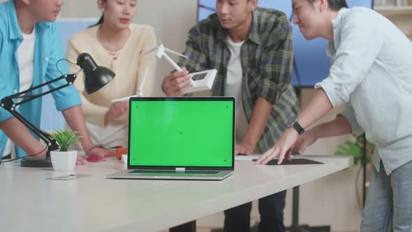 Green Screen Laptop Is On The Table While Engineers Group Having A Meeting About The Wind Turbine