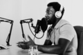 African man recording a podcast using microphone and headphones from his home studio - PhotoDune Item for Sale