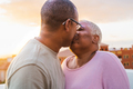 Happy Latin senior couple having romantic moment kissing on rooftop during sunset time - PhotoDune Item for Sale