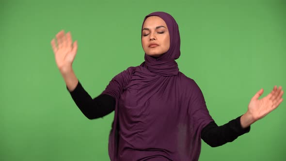 A Young Beautiful Muslim Woman Dances and Waves Hands to Slow Music  Green Screen Background