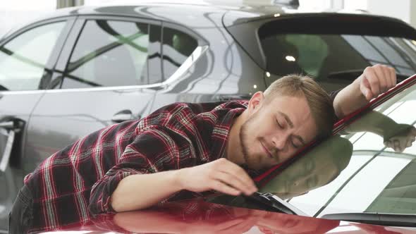 Happy Man Stroking His New Car Gently Smiling Showing Thumbs Up at the Dealership