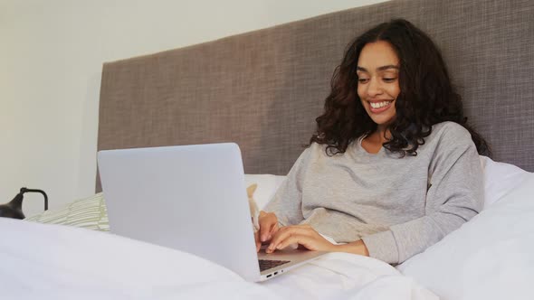 Happy woman using her laptop while sitting on bed with her cat 4K 4k