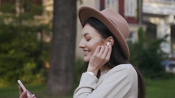 Girl in Stylish Hat Wearing Earphones and Enjoying Music