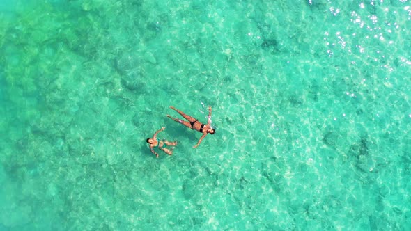 Beautiful smiling ladies on photoshoot having fun at the beach on summer white sand and blue 4K back