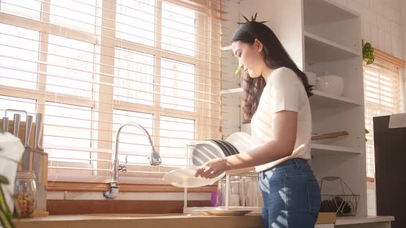 Asia lady washing dishes while doing cleaning in the kitchen at house