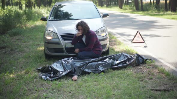 Wide Shot Desperate Caucasian Man Crying Over Corpse of Dead Woman Sitting at Car on Roadside