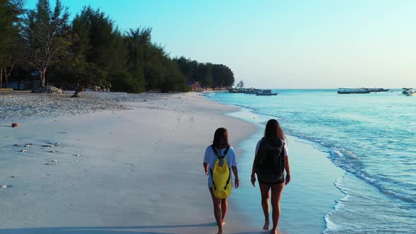Beautiful ladies happy together on idyllic coast beach adventure by shallow ocean and bright sand ba