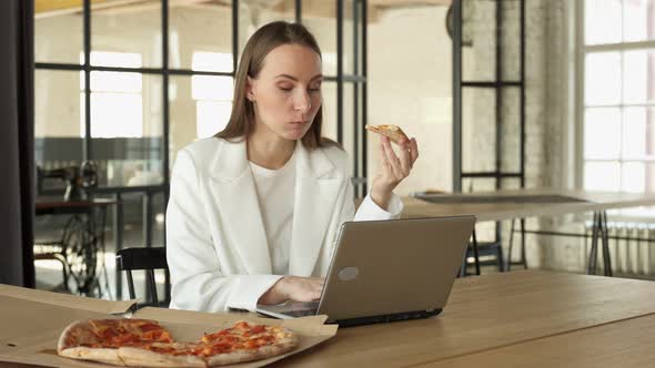 Business Woman Working an Office Desk with a Laptop and Having a Lunch Break with a Tasty Pizza