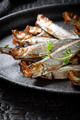Salty smoked sprats on a black plate and burnt table. - PhotoDune Item for Sale