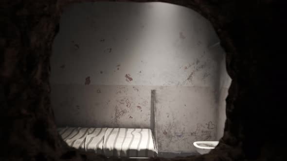 Animation of single old grunge locked prison cell with a hole in the wall.