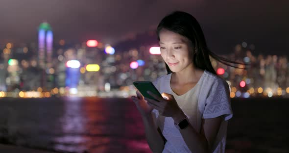 Woman use of smart phone in Hong Kong at night