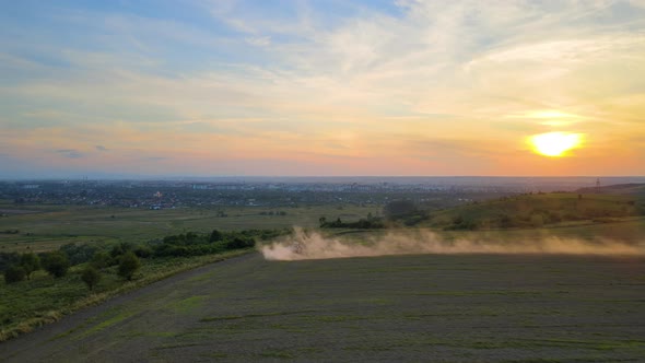 Tractor Spraying Fertilizers with Insecticide Herbicide Chemicals on Agricultural Field at Sunset