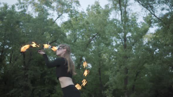 Slim Woman in Mask Dancing, Performing a Show with Fireball Standing on the Riverbank