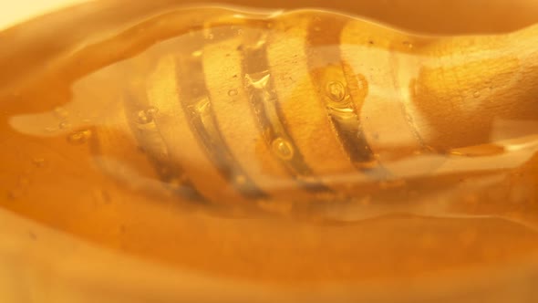 Liquid Organic Honey Dripping from Above to a Honey Dipper in Wooden Bowl