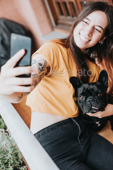 g care of her french bulldog with tongue out on home.Puppy observing concentrated looking the city.Playful,humorous and cheerful friendship partner.