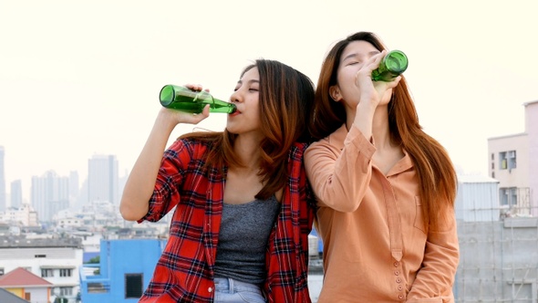 Young Asian woman lesbian couple clinking bottles of beer party on the rooftop.