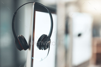 Shot of a pair of headsets sitting on the edge of a computer screen in an empty office
