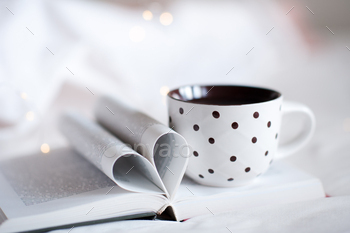 Paper book with folded haert shape pages and cup of coffee